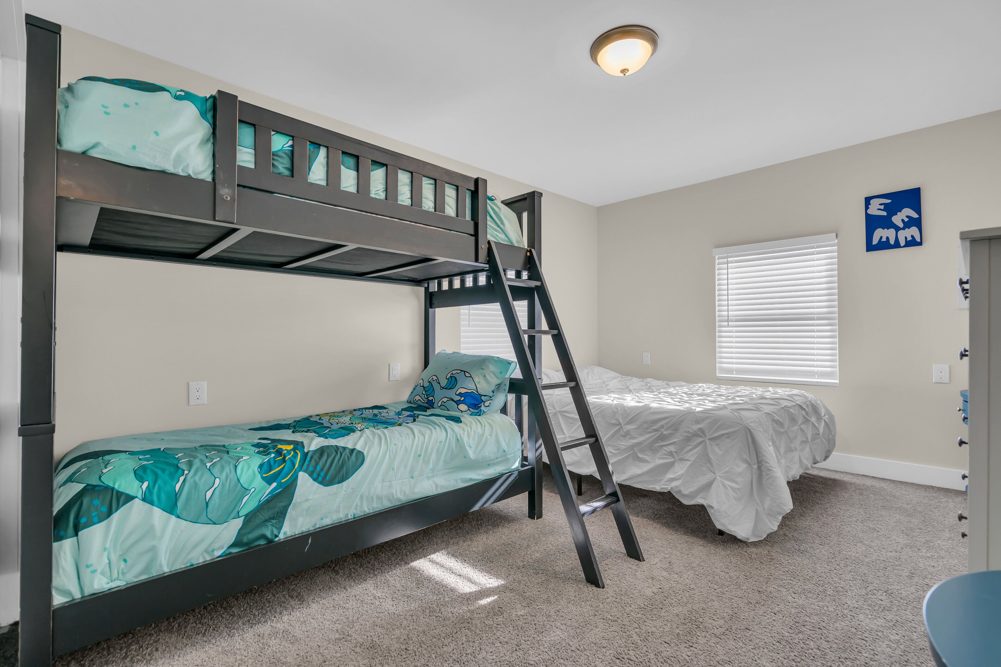 A bunk bed room with a ladder, a window with blinds, and a door with a handle.