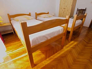 Une pièce comprenant deux lits superposés en bois, une armoire en bois et une chaise en bois.