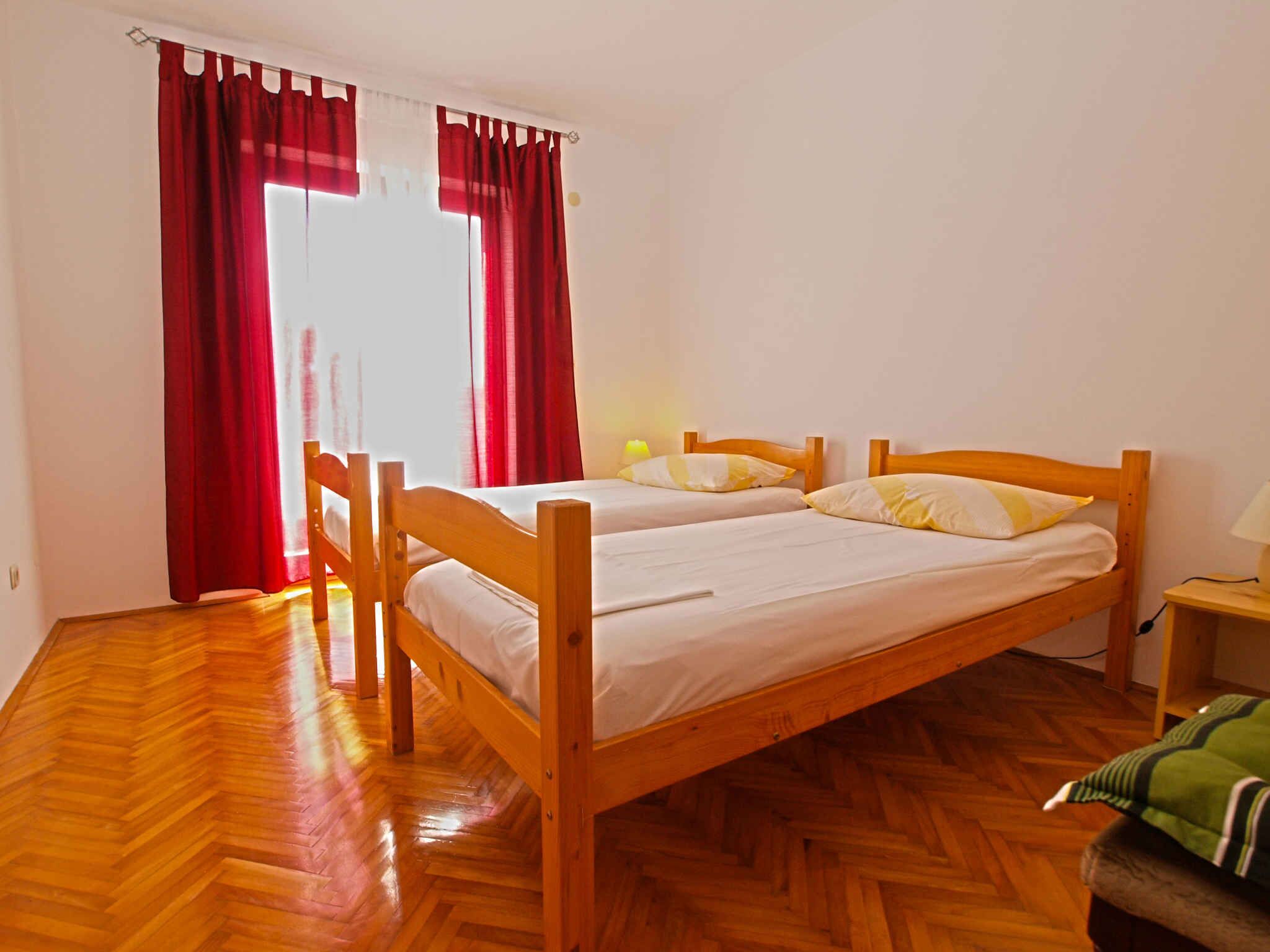 A room with a wooden bed, red curtains, and a wooden floor.
