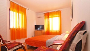 Hotellihuone, jossa on sänky, televisio ja kaksi tuolia.