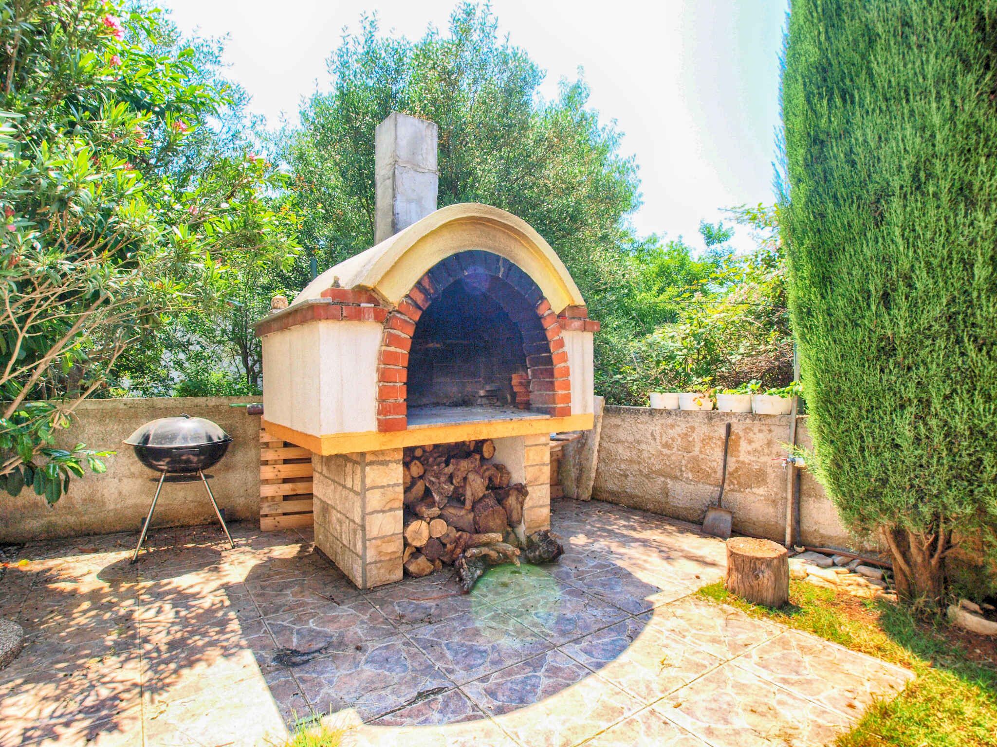 An outdoor brick oven with a chimney, a grill, and a stone patio.