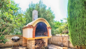 An outdoor brick oven with a chimney, a grill, and a stone patio. - (Štinjan)