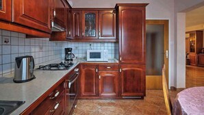 A compact kitchen with wooden cabinets, a microwave, a stove, and a kettle. - Holiday apartment with air conditioning (Pula)