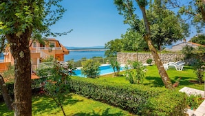 Vista della piscina con una visuale aperta sul mare, un muro in pietra e un prato curato.