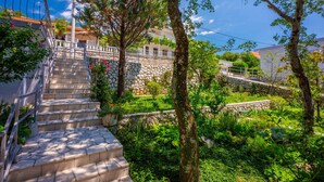 Una scala in pietra che conduce a un edificio con un muro in pietra e una ringhiera in metallo.