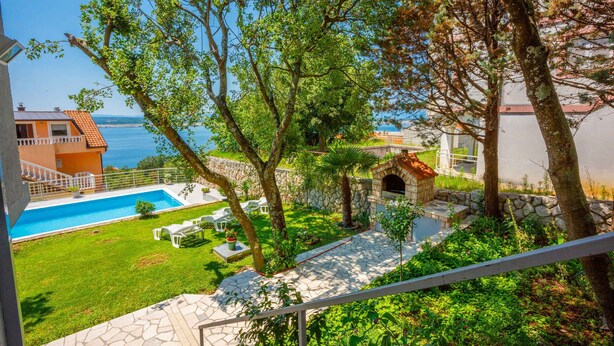 Area piscina con vialetto in pietra, posti a sedere all'aperto e vista sul mare.