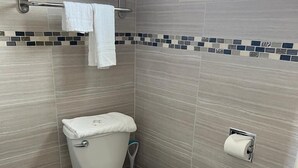 A bathroom with a toilet, a towel rack, and a toilet paper holder. - Aaron Motel (Portland)