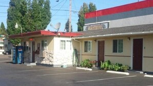 A motel with a red roof, a satellite dish, and a parking lot. - Aaron Motel (Portland)