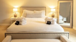 A neatly made bed with white linens, two bedside tables with lamps, a large mirror, and a chair. - The Palmetto @ Park Circle - 10 Minutes From Downtown, The Palmetto @ Park Circle (North Charleston)