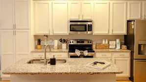 A kitchen with white cabinets, a granite countertop, a stainless steel oven, a microwave, a refrigerator, and a sink. - The Palmetto @ Park Circle - 10 Minutes From Downtown, The Palmetto @ Park Circle (North Charleston)