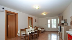 A dining area with a table, chairs, and a kitchen area with cabinets and a countertop.