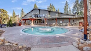Un edificio con area piscina, posti a sedere all'aperto e patio coperto.