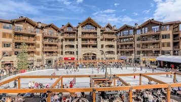 A multi-story hotel with a central courtyard, balconies, and a ski lift visible in the background.
