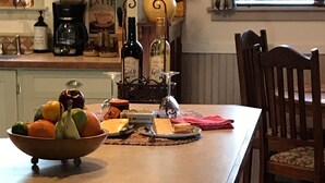 Una cocina con una isla central, una mesa de comedor con sillas y un ventanal con cortinas.