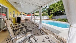 Un patio cubierto con piscina, mobiliario exterior y vista a la piscina.