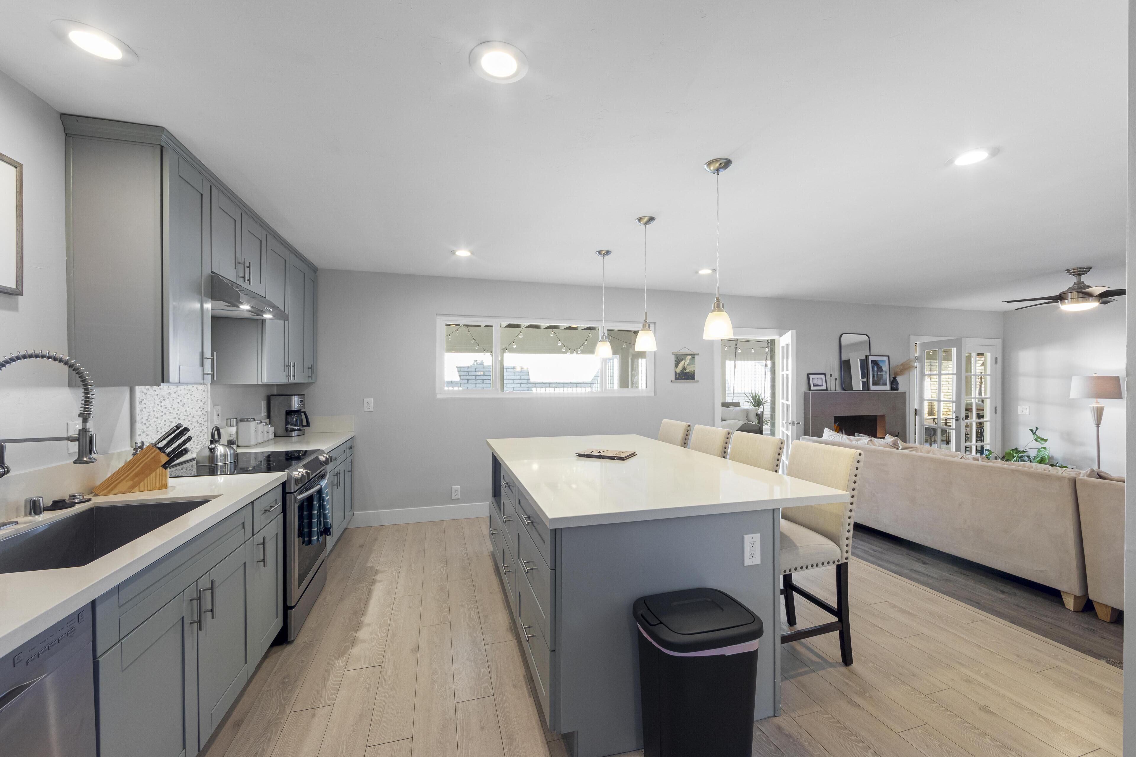 A modern kitchen with grey cabinets, a central island, and pendant lighting.
