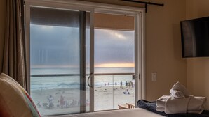 A hotel room with a bed, a bench, and a view of the beach.