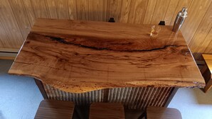Une table en bois dotée d’un motif de fissures original, accompagnée de quatre chaises.