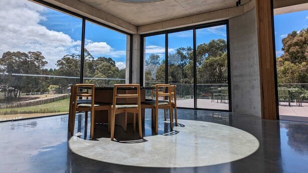 A spacious room with a round skylight, large windows, and a central table with chairs. - Unveil a masterpiece in architectural design!  (Hepburn)