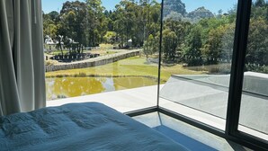 A bedroom with a large window offering a view of a park, a bridge, and a body of water. - Unveil a masterpiece in architectural design!  (Hepburn)
