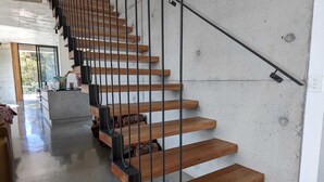 A modern staircase with wooden steps and black metal railings. - Unveil a masterpiece in architectural design!  (Hepburn)