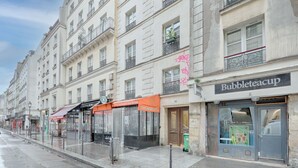 A street view with a Bubbleteacup store, a cafe, and a building with balconies. - Appartement Martino - Welkeys (Paris)