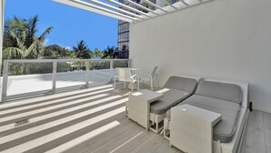 Un balcone con un divano bianco, due poltrone e un tavolino.