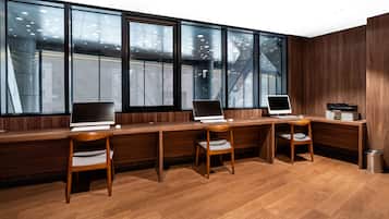 A modern office with three desks, each with a computer and a chair.