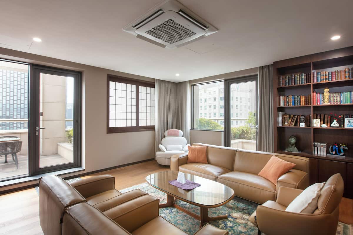 Un salon moderne avec des canapés en cuir, une table basse en verre et une bibliothèque remplie de livres.