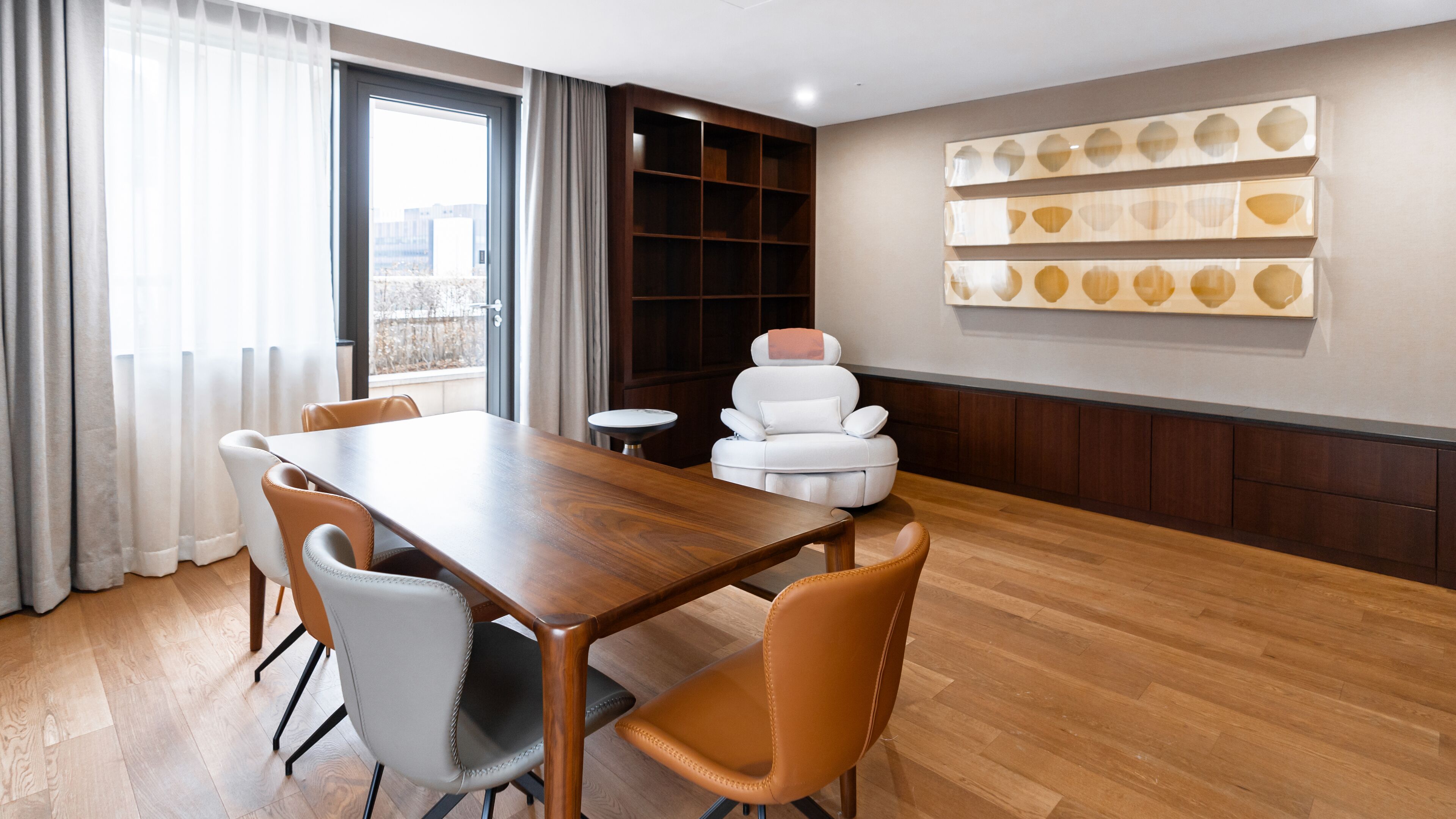 A modern dining area with a wooden table and chairs, a sofa, and a bookshelf.