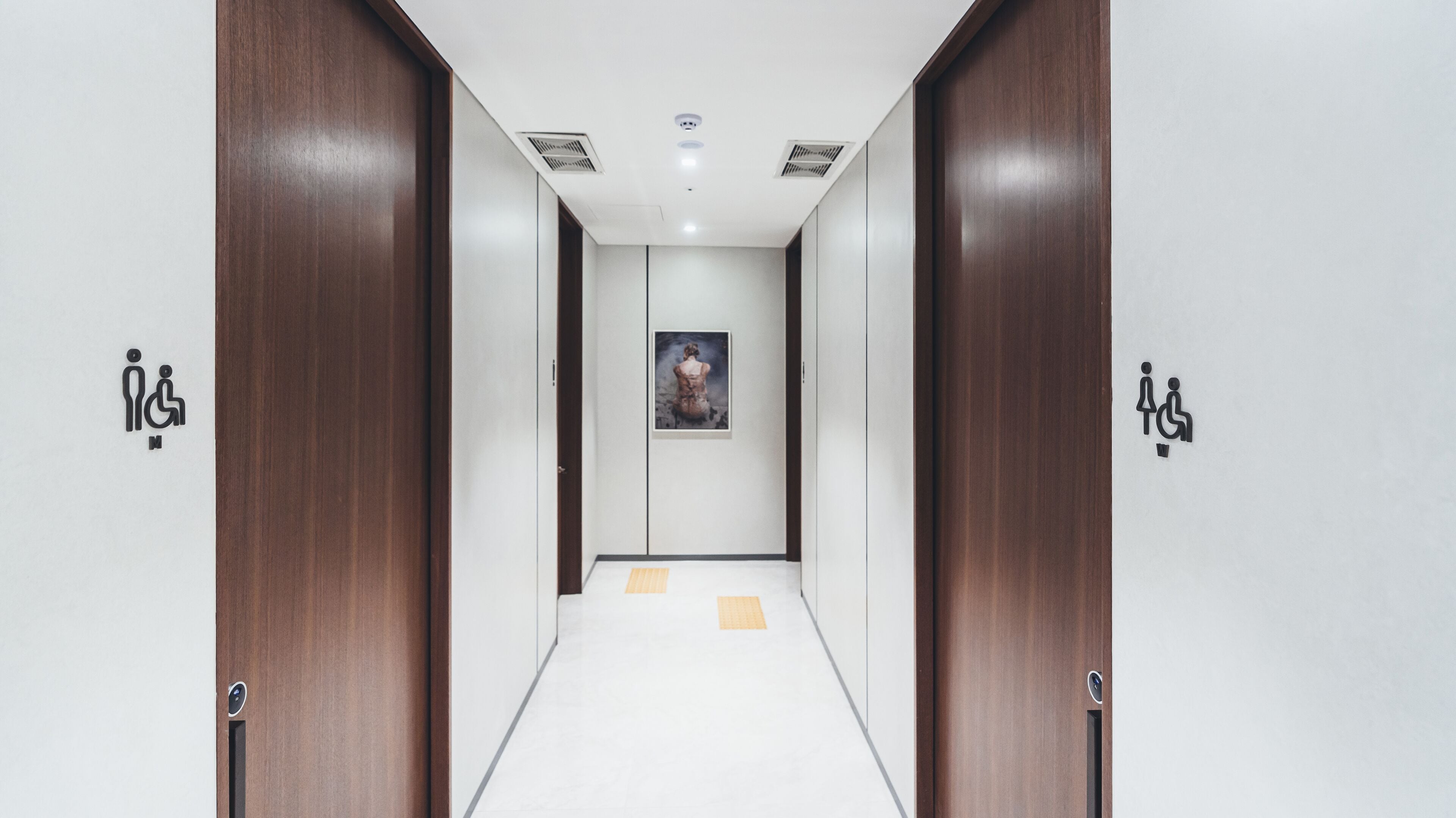 A hallway with two doors on either side, each marked with a wheelchair accessibility symbol.