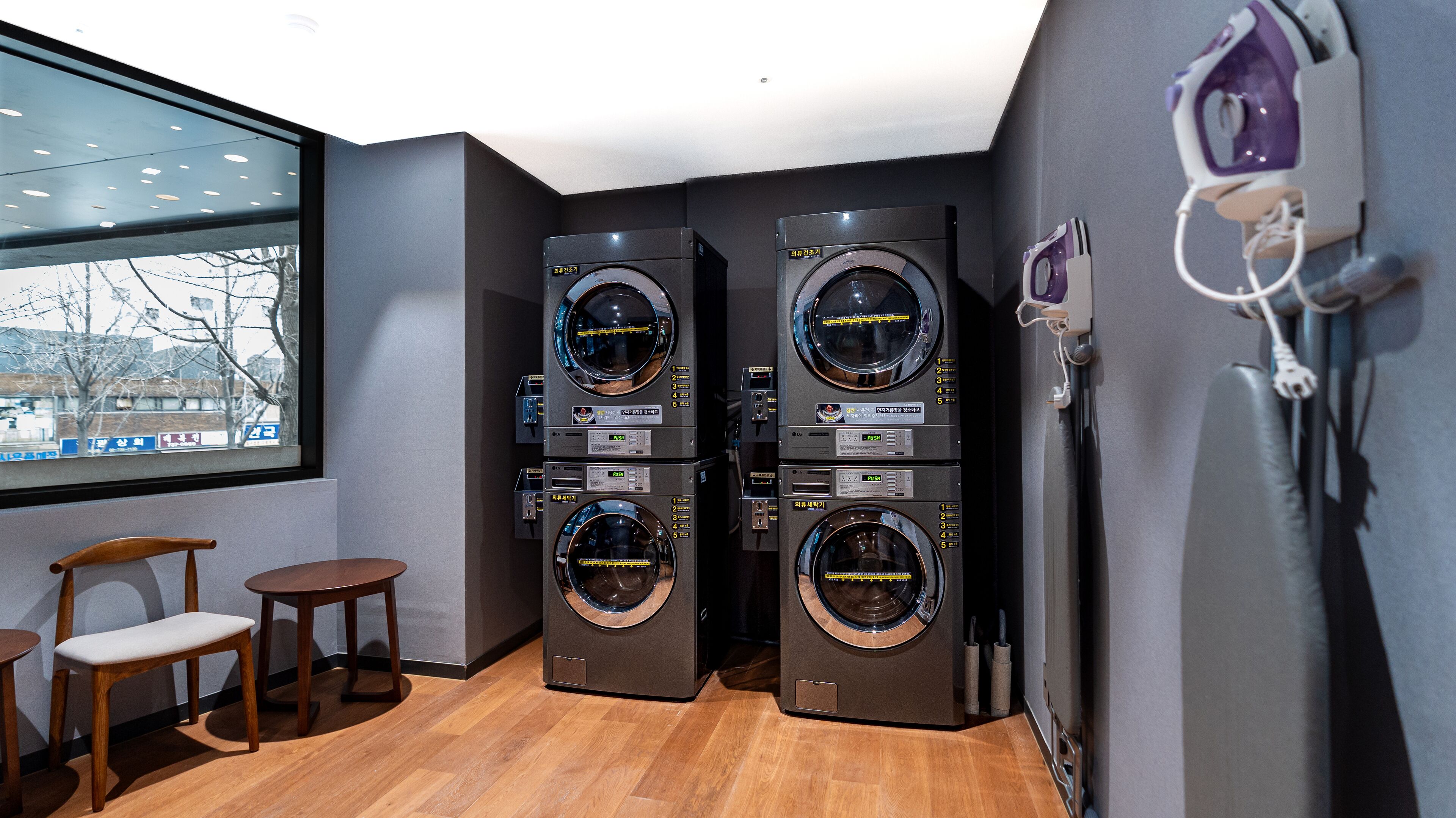 A laundry room with two stacked washing machines, a small table, and chairs.