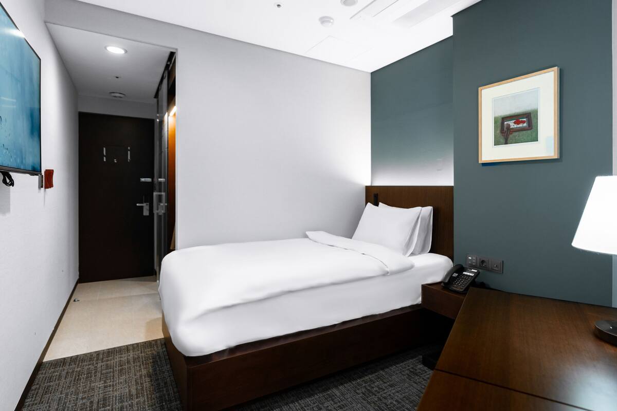 Une chambre d’hôtel avec un lit, une table de chevet, une lampe et un tableau au mur.