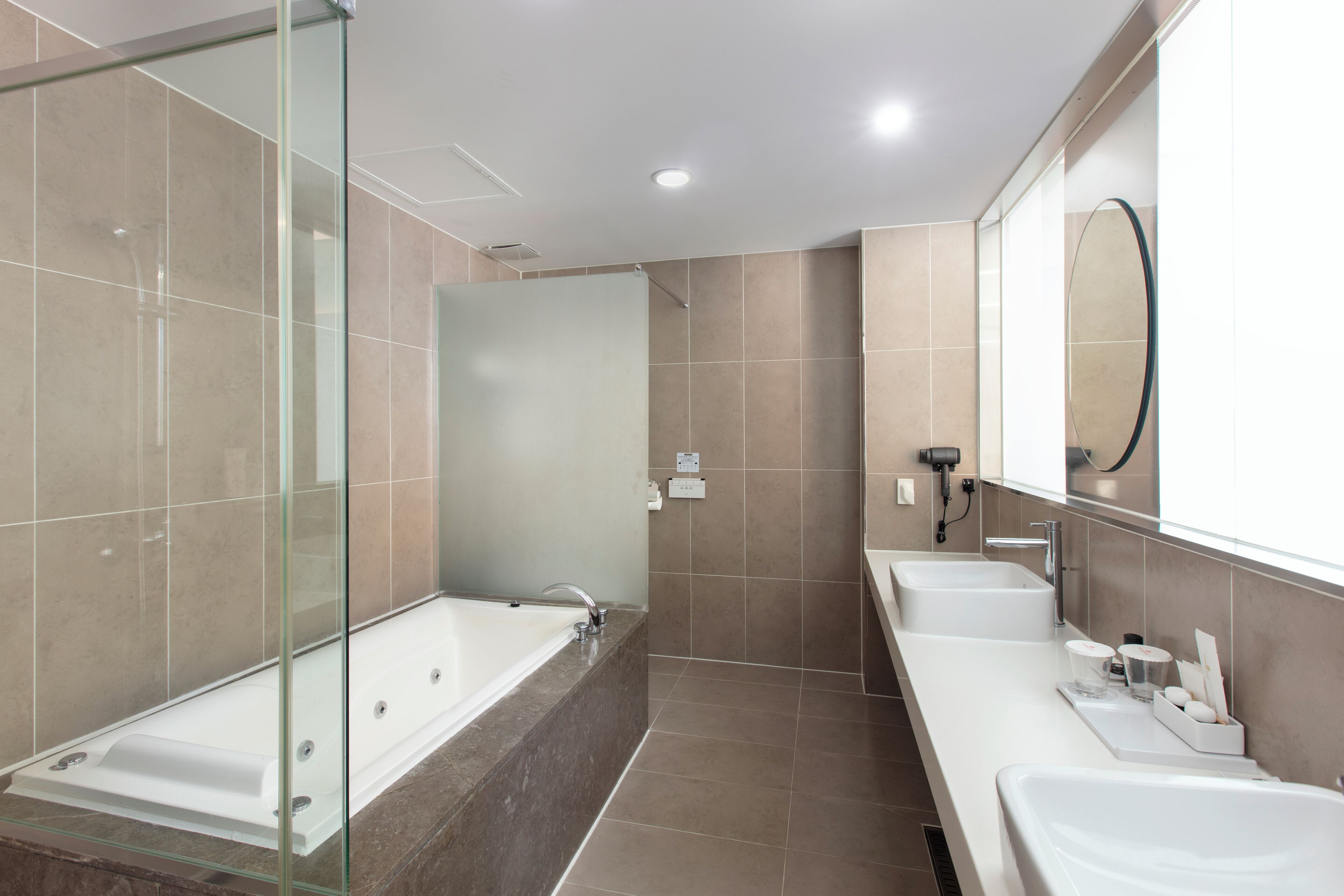 A modern bathroom with a glass-enclosed shower, a freestanding bathtub, and a double sink vanity.