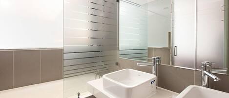 Un baño moderno con un espejo grande, dos lavamanos y una bañera.