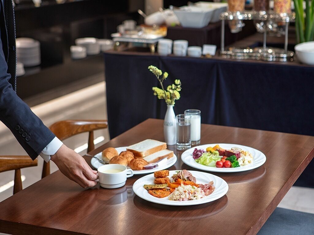 A breakfast buffet with various dishes, including eggs, meats, and vegetables, on a wooden table.