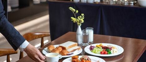 A breakfast buffet with various dishes, including eggs, meats, and vegetables, on a wooden table.