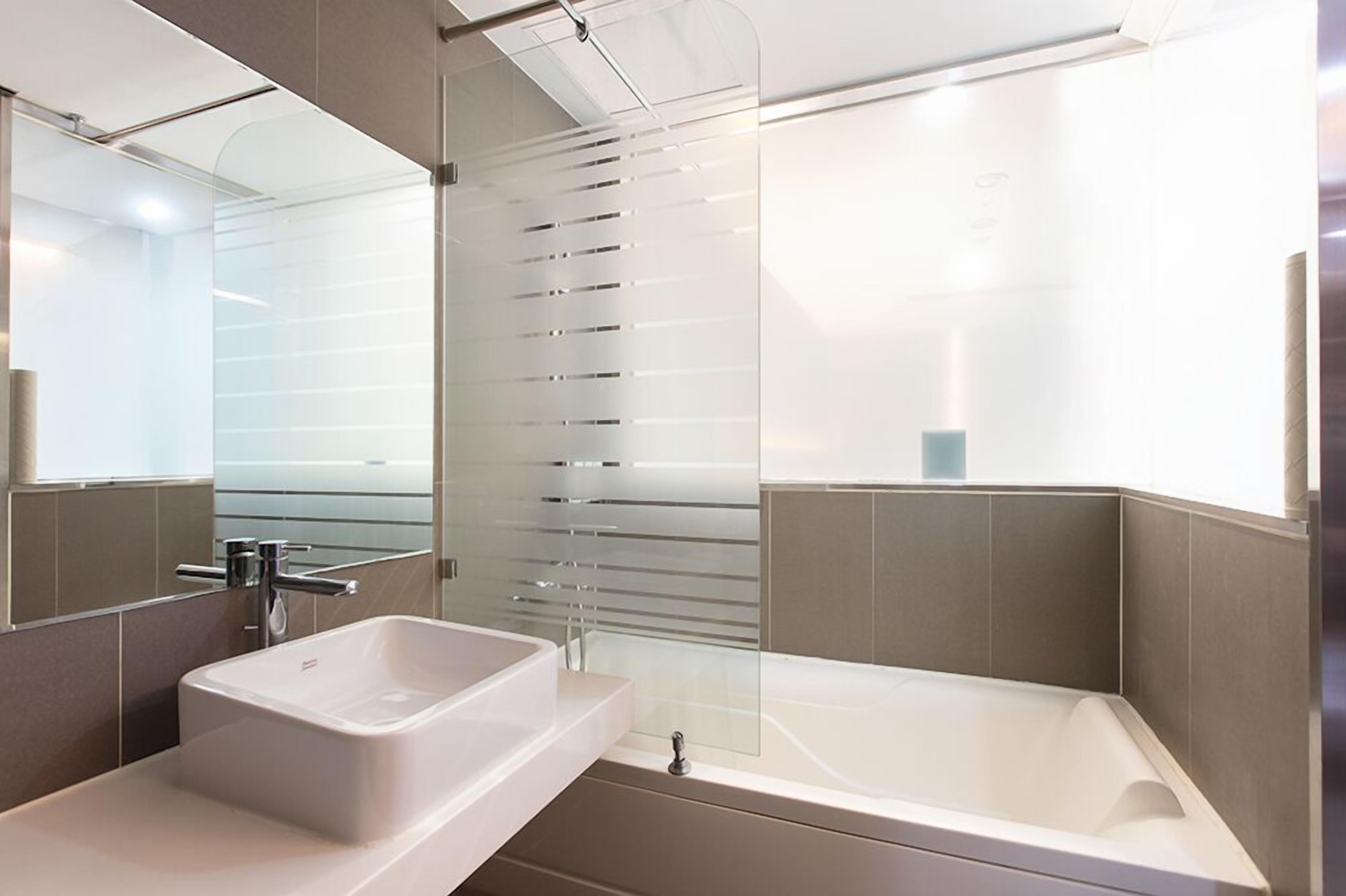 Une salle de bain moderne avec un grand miroir, un lavabo et une baignoire.