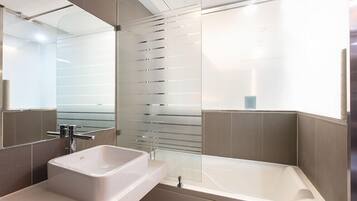 Une salle de bain moderne avec un grand miroir, un lavabo et une baignoire.
