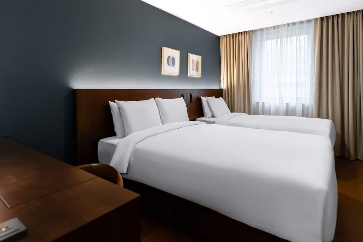 Une chambre d’hôtel avec un lit, un bureau et une lampe.
