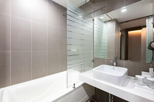 A modern bathroom with a bathtub, a sink, and a glass partition.
