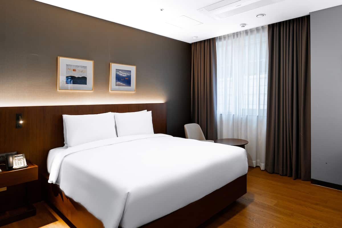 Une chambre d’hôtel avec un grand lit, un bureau avec un téléphone et une chaise.