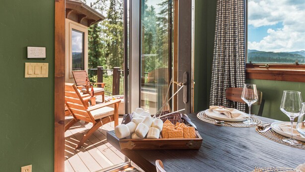 Un comedor con una mesa lista para dos, un banco de madera y vistas al exterior.