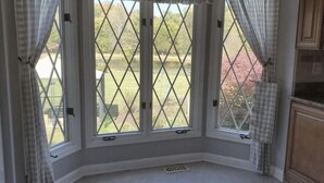 A room with a large window featuring a diamond-patterned view of a garden and a pond. - Cozy cottage with a beautiful waterfront view. Pet friendly! 45 min from DC.   (Catharpin)