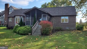 A two-story house with a front porch, a chimney, and a well-maintained lawn. - Cozy cottage with a beautiful waterfront view. Pet friendly! 45 min from DC.   (Catharpin)