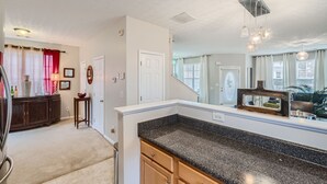 A kitchen with a granite countertop, white walls, and a large window.