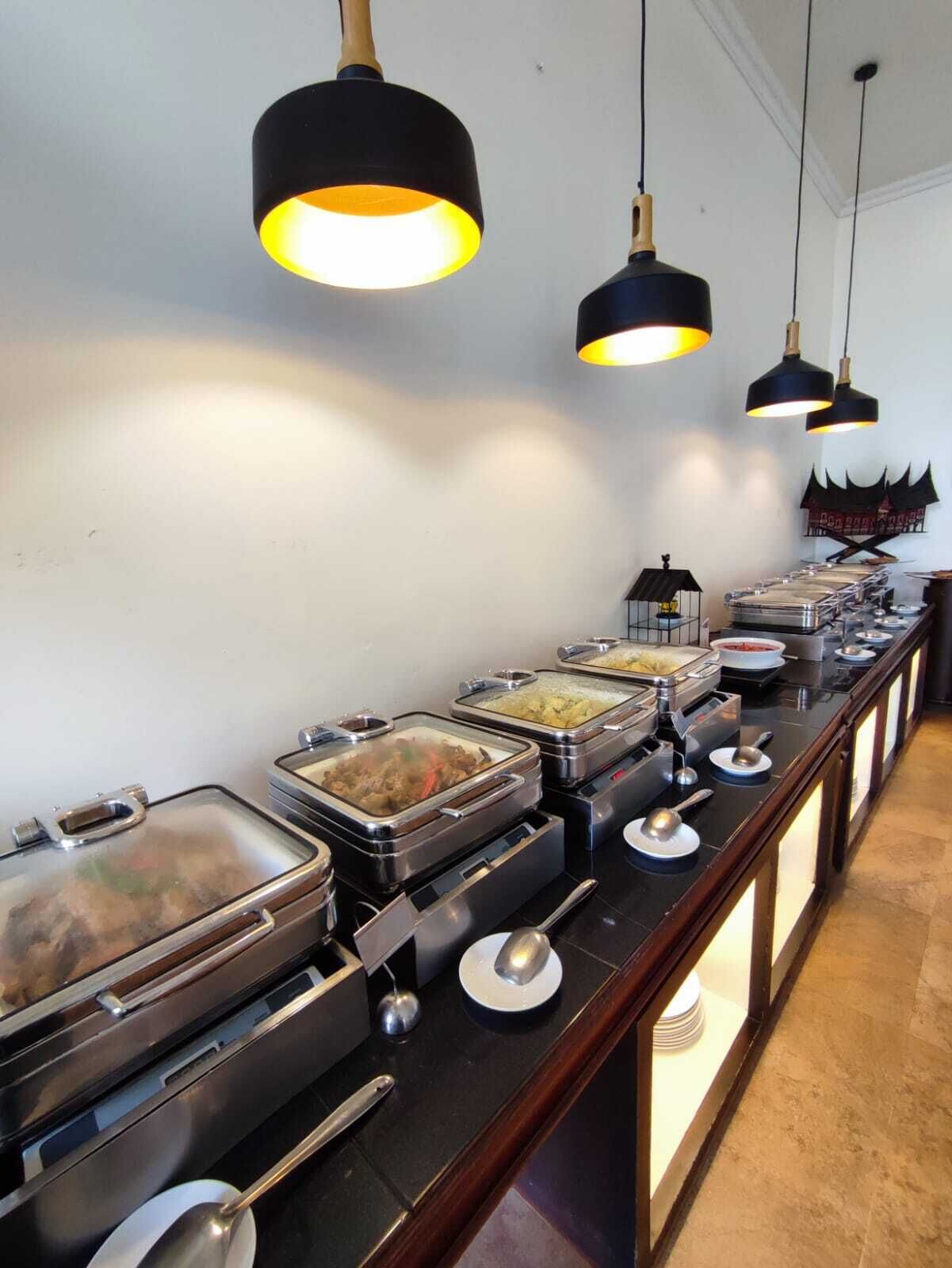 A buffet setup with multiple food stations, each with covered dishes and serving utensils.