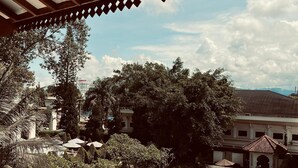 A swimming pool with a view of a hotel and surrounding greenery. - Monopoli Hotel Bukittinggi (Bukittinggi)