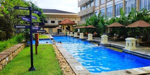 A swimming pool with a signpost indicating directions to various cities. - Monopoli Hotel Bukittinggi (Bukittinggi)