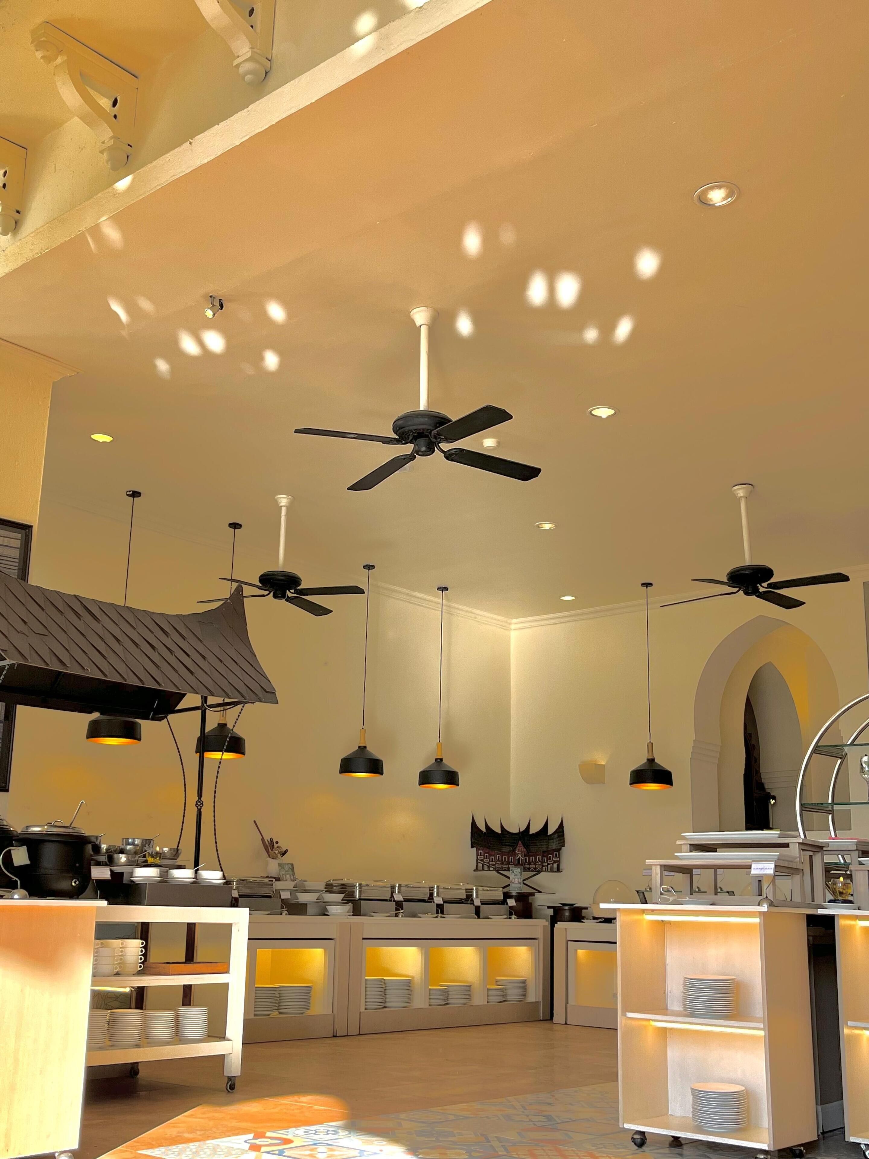 A modern kitchen with ceiling fans, pendant lights, and a buffet setup.